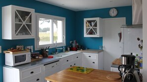 A kitchen with white cabinetry, a microwave, a coffee maker, and a clock on the wall.