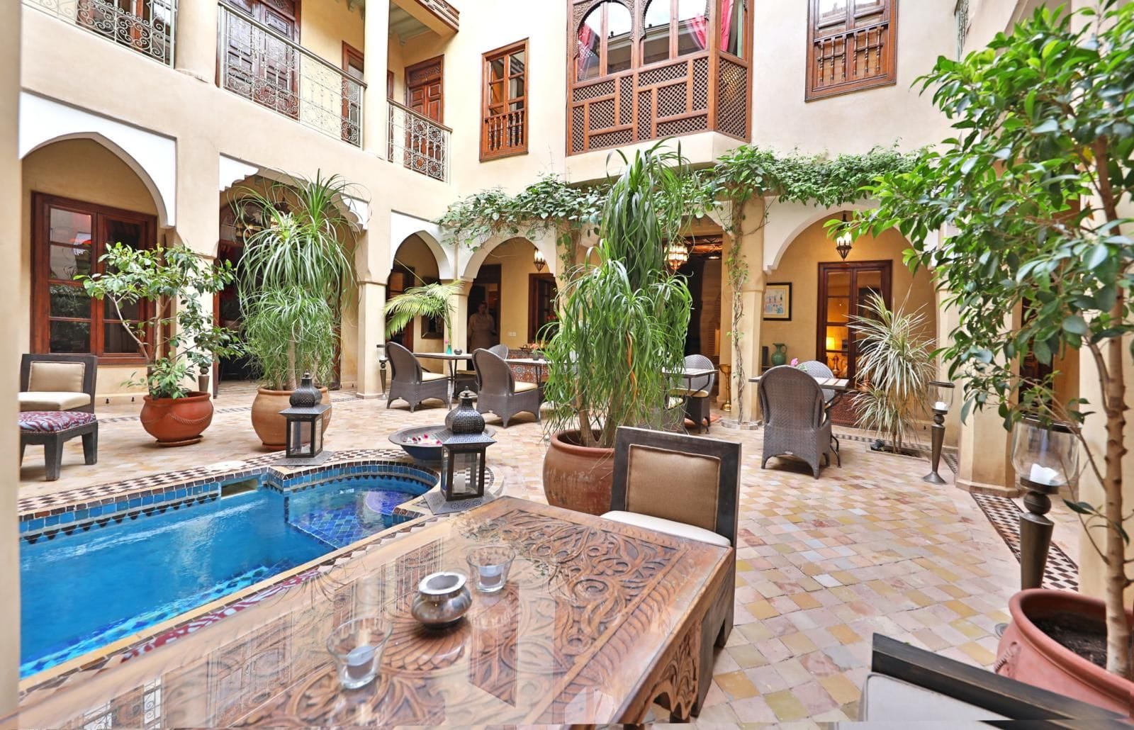 A courtyard with a pool, outdoor seating, and potted plants.
