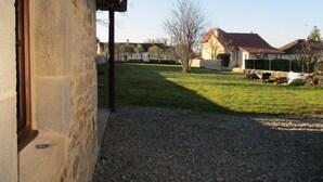 Un bâtiment en pierre avec une allée en gravier et une cour gazonnée.