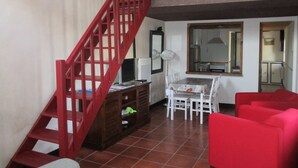 Un salon avec un escalier rouge, une table à manger avec des chaises et un canapé rouge.