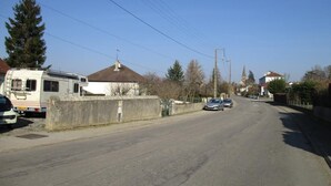 Une rue résidentielle bordée de maisons, avec un camping-car garé et des voitures.