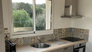 Une cuisine moderne dotée d’une fenêtre, d’un évier en acier inoxydable et d’un lave-vaisselle.