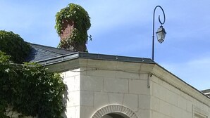 A small building with a white door and arched window, surrounded by a paved area with outdoor furniture. - Beautiful studio between Chateau and Loire (Saumur)