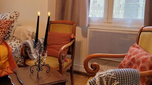 A cozy living room with a patterned rug, a wooden table with candles, and a large window with curtains. - Beautiful studio between Chateau and Loire (Saumur)