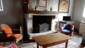 Una sala de estar acogedora con chimenea, una mesa de madera y sillas coloridas a rayas.