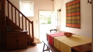Una escalera de madera que lleva a una habitación con una mesa, un banco y una lámpara fijada a la pared.