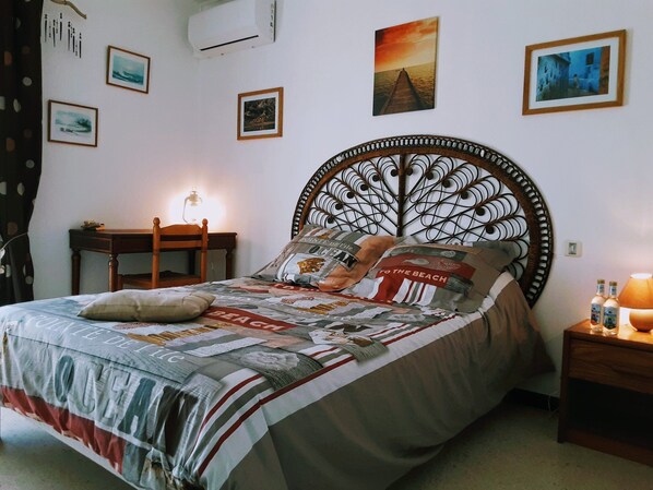 A neatly made bed with a patterned bedspread, a decorative headboard, and a bedside table with a lamp.