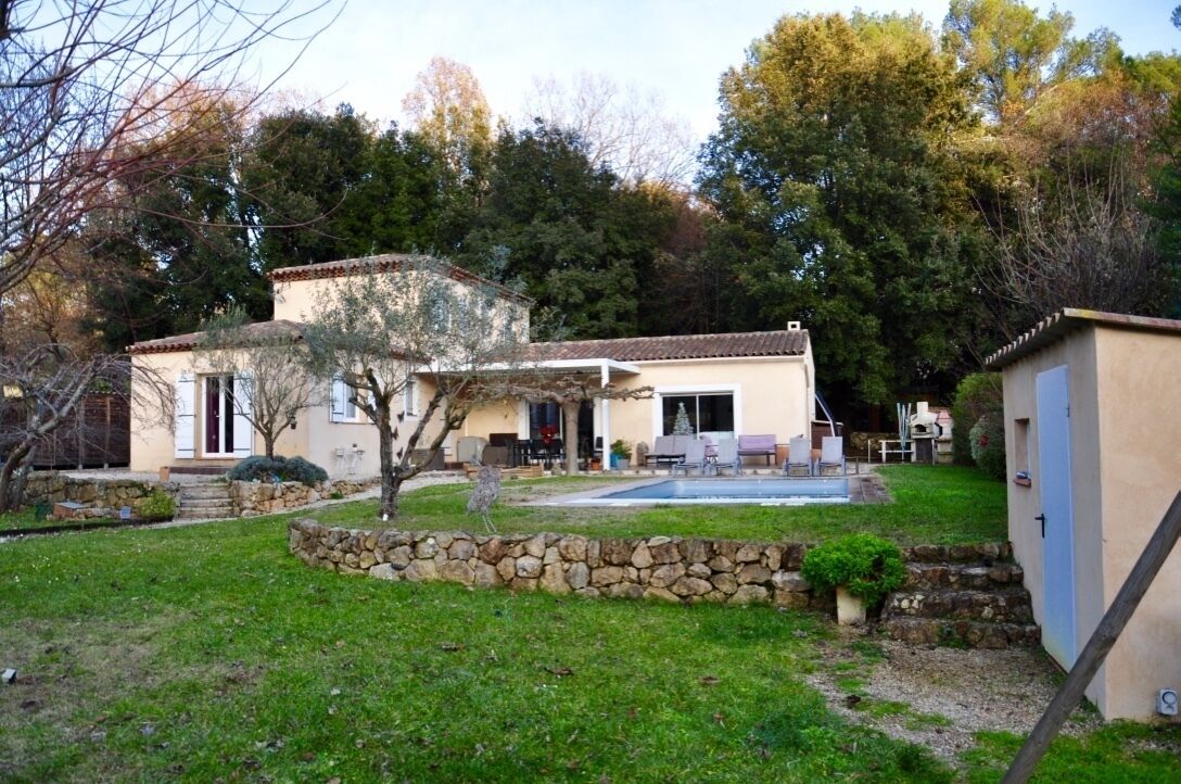 A house with a stone wall, a pool, and a garden.