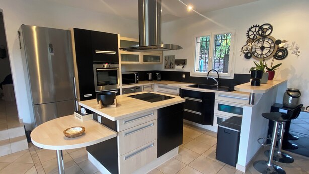 A modern kitchen with a central island, stainless steel appliances, and a decorative wall clock.