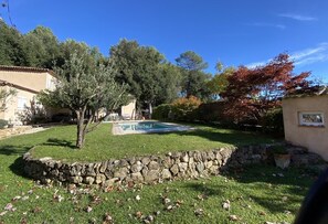 A backyard with a swimming pool, stone wall, and trees. - Magnificent 4-bedroom family villa in the heart of the Côte d'Azur (Roquefort-Les-Pins)