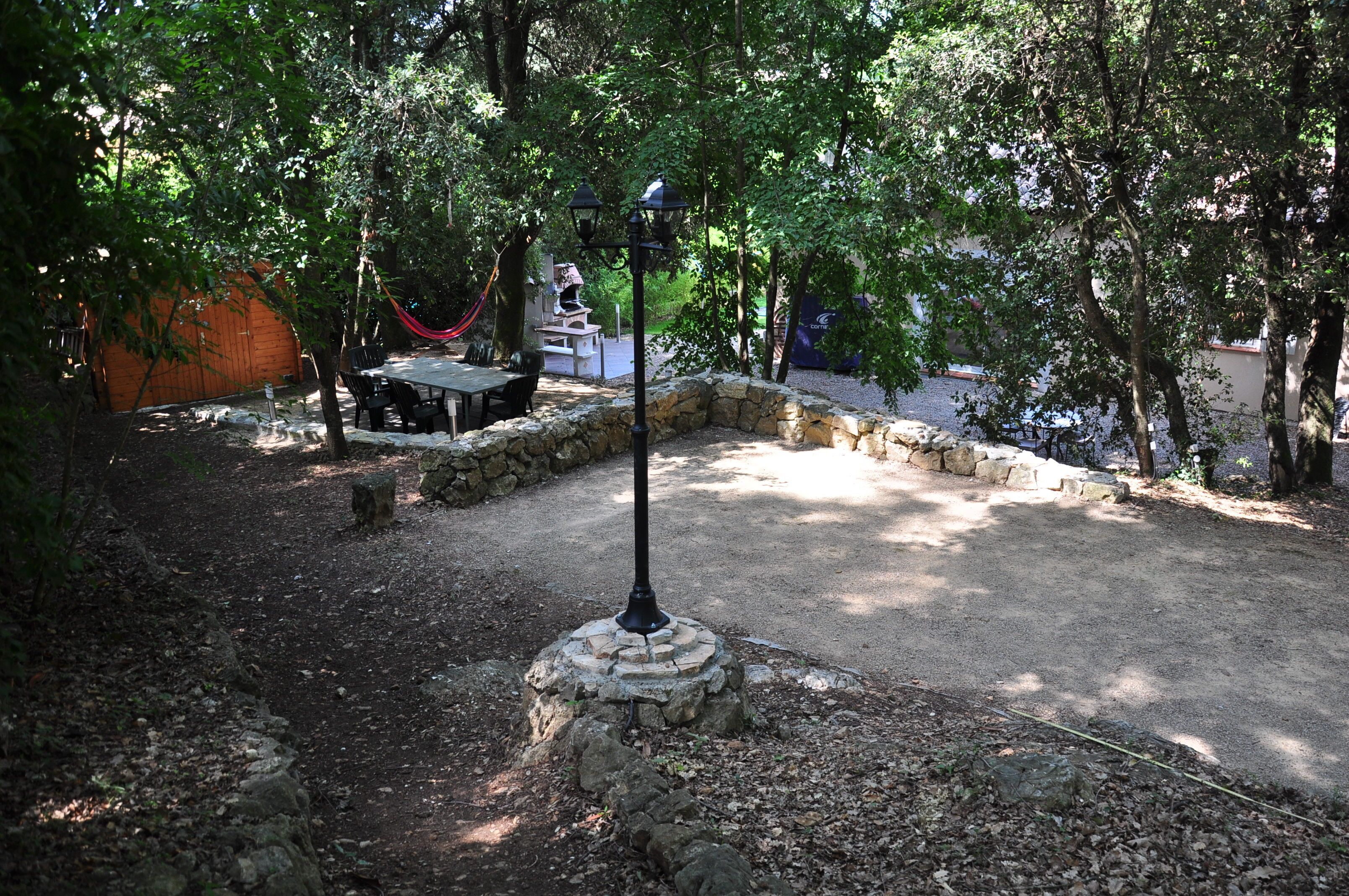 Un patio al aire libre con un hogar a leña de piedra, una hamaca y una mesa con sillas.