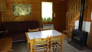 L’intérieur d’un chalet en bois comprend une table à manger, des chaises, un canapé, une cheminée et un escalier.