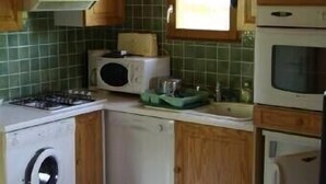 Une cuisine compacte avec des meubles en bois, un four à micro-ondes, une cuisinière et un lave-linge.