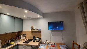 A modern kitchen with a wooden countertop, a sink, and a dining area with a table. A flat-screen TV is mounted on the wall above the dining area. - Rental in Notre Dame de Bellecombe, Espace Diamant, 500m from the ski lifts.  (notre dame de bellecombe)