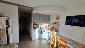 A compact kitchen with a dining area, wooden flooring, and a TV mounted on the wall. - Rental in Notre Dame de Bellecombe, Espace Diamant, 500m from the ski lifts.  (notre dame de bellecombe)