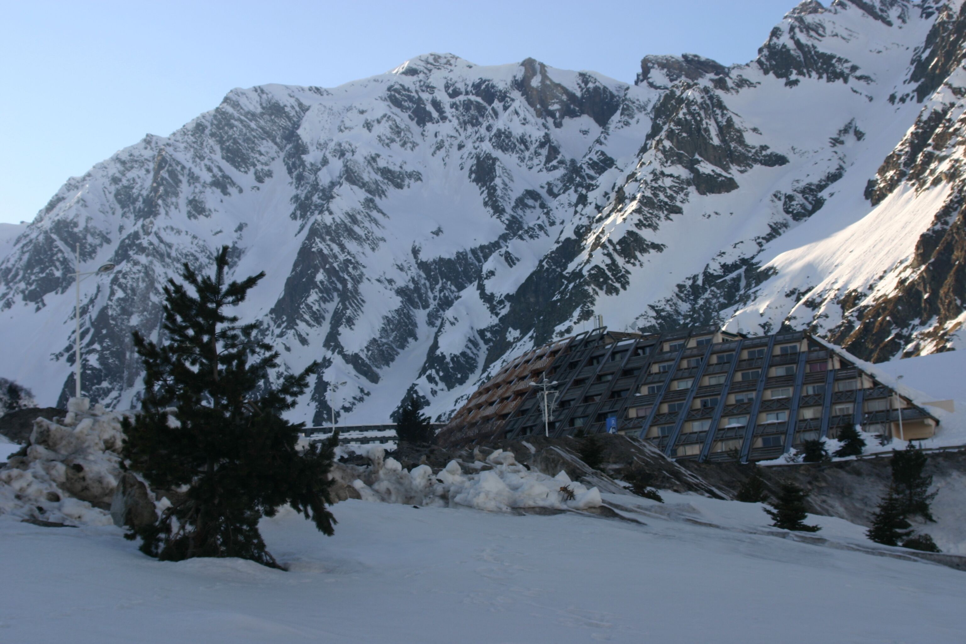 Une montagne enneigée, avec un bâtiment visible au premier plan.