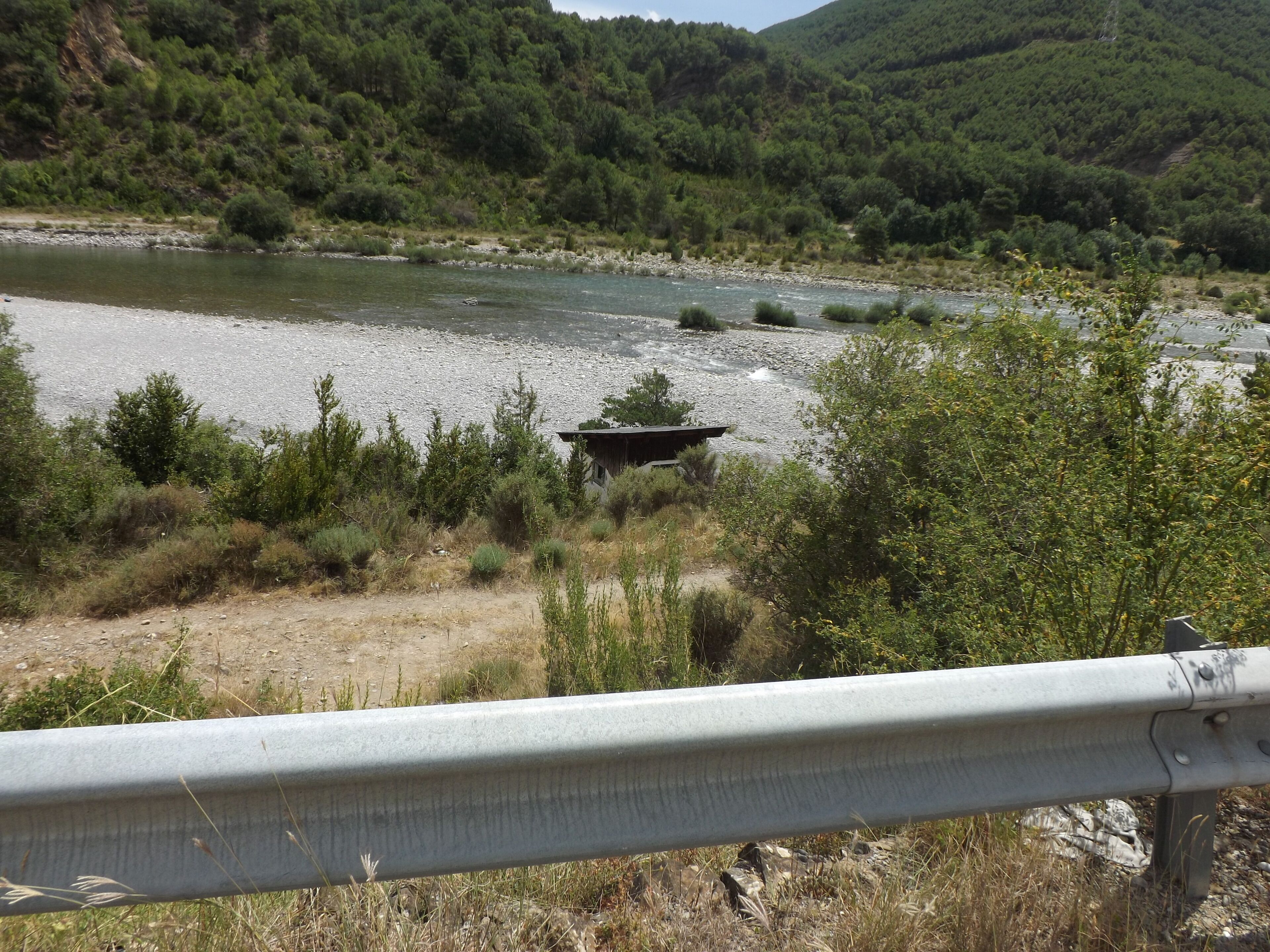 Ein Fluss mit einem Boot, umgeben von Grünflächen und Hügeln.