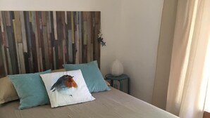 Et soveværelse med seng, sengegavl, natbord og lampe.