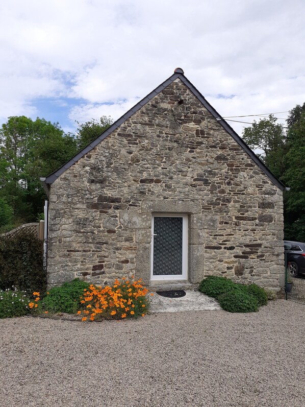 A stone building with a triangular roof, a small window with a metal grid, and a gravel driveway. - Ti Bihan at Pors Jaffrennou (Scrignac)