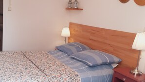 Ein Schlafzimmer mit einem hölzernen Kopfteil, einer gemusterten Tagesdecke und zwei Nachttischlampen.
