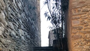 Eine steinerne Treppe in einem schmalen Gang, der von rauen Steinwänden gesäumt wird.