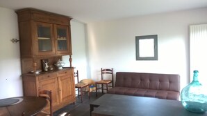 A living room with a wooden cabinet, a brown sofa, a table, and two chairs.