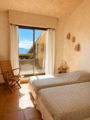 Une chambre avec un lit, une chaise, un bureau et une vue sur la mer.