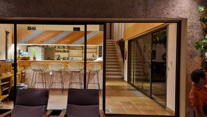 A modern interior with a kitchen area, bar stools, and a staircase leading to an upper level. - 200 meters from Aiguebelle beach -superb view of the islands- private Jacuzzi (Le Lavandou)