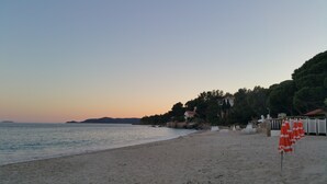 A beach with a clear sky, calm sea, and a row of orange umbrellas. - 200 meters from Aiguebelle beach -superb view of the islands- private Jacuzzi (Le Lavandou)
