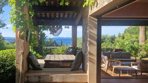 A covered outdoor seating area with a view of the sea, wooden furniture, and a pergola structure. - 200 meters from Aiguebelle beach -superb view of the islands- private Jacuzzi (Le Lavandou)