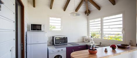 A compact kitchen with a washing machine, a microwave, a toaster, and a sink.
