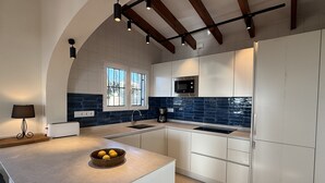 A modern kitchen with white cabinets, a blue backsplash, a built-in microwave, and a large window with decorative iron bars. - The perfect holidays Villa - great views - Beach near by.  (Altea)