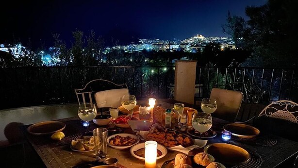 A table set for a meal with various dishes, glasses, and a candle, overlooking a cityscape at night. - The perfect holidays Villa - great views - Beach near by.  (Altea)
