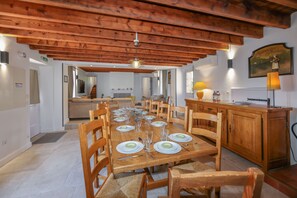Ein Essbereich mit Holztischen und -stühlen, ein Küchenbereich mit einer Holzausstattung und eine Treppe zu einer oberen Ebene.