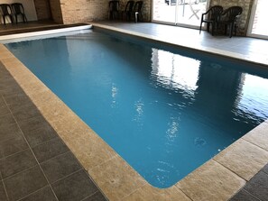 Swim laps in the pool surrounded by a tiled deck and a brick wall.