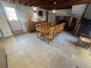 Una zona pranzo con tavolo e sedie in legno, una cucina con mobili in legno, un camino a scacchi e una scala.