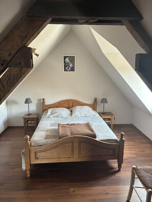 Cozy attic bedroom with a wooden bed, bedside tables, and a framed artwork.