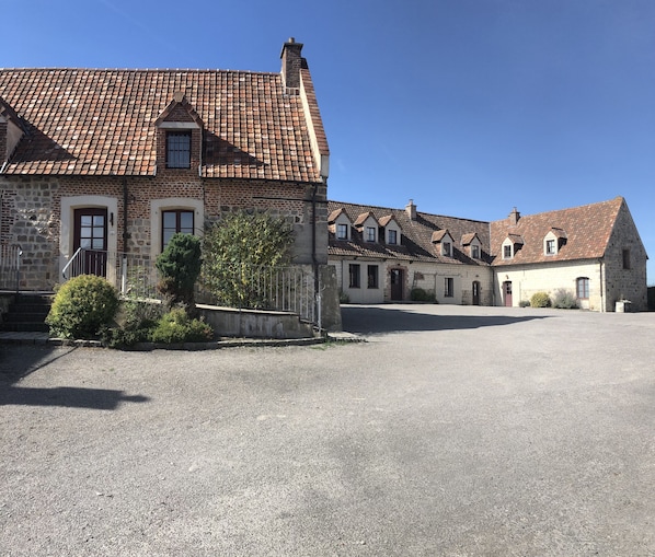 Traditional building with a classic facade, evenly spaced windows, and a central entrance, set amidst a manicured garden.