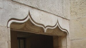 A doorway with a decorative arch, leading to a dark interior. - Grand T1 in hyper-center in a classified building (Dijon)