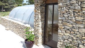 A stone building with a glass door and a greenhouse structure in the background. - Charming maisonette ****, Pool with sea view, Golf, Spa, Quiet, Open spaces (Bouches-du-Rhône)