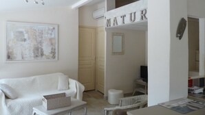 A modern living room with a white sofa, a small table, and a wall-mounted air conditioning unit. - Charming maisonette ****, Pool with sea view, Golf, Spa, Quiet, Open spaces (Bouches-du-Rhône)