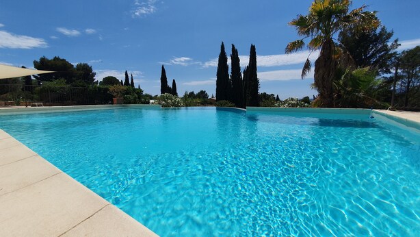 A clear blue swimming pool with a view of tall trees and a clear sky. - Charming maisonette ****, Pool with sea view, Golf, Spa, Quiet, Open spaces (Bouches-du-Rhône)