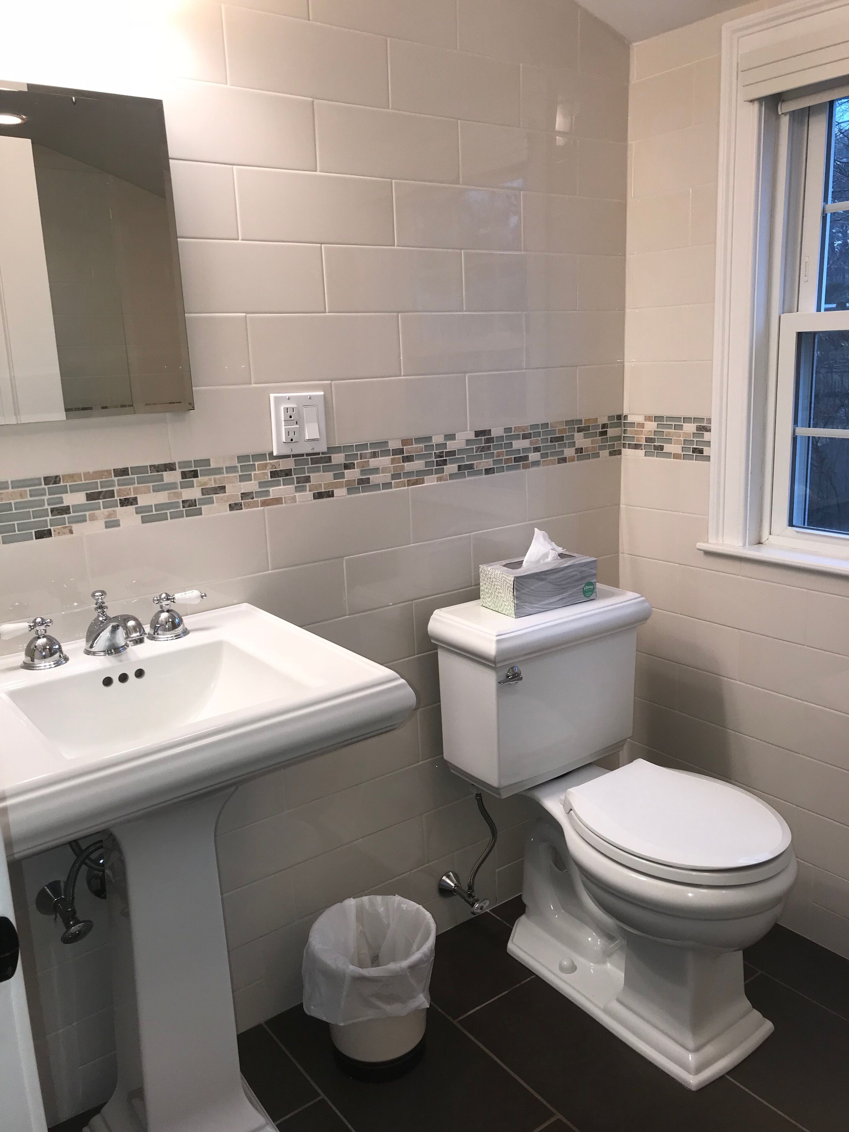 Une salle de bain avec un lavabo blanc, des toilettes et un miroir au-dessus du lavabo.