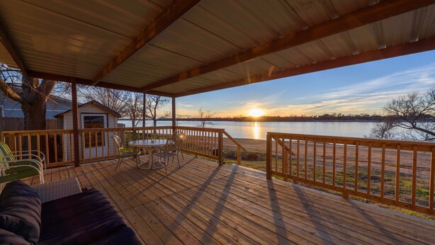 A wooden deck with a covered area, a table, chairs, and a sofa.
