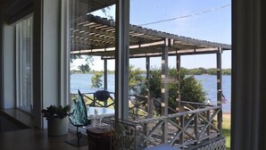 A covered porch with a view of a lake and trees.