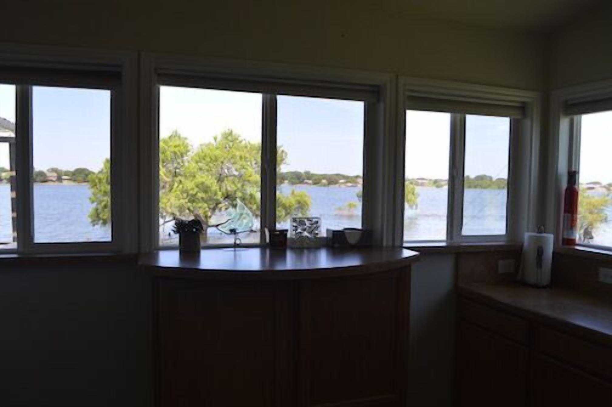 A room with a view of a lake, a wooden cabinet, and a small table with a potted plant.