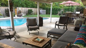 A covered patio area with a pool, outdoor seating, and a barbecue setup. - Chico Family Retreat with Pool~Bocce~Hot-tub~Lounge. Near park, downtown & CSU (Chico)
