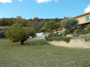 Un paysage rural avec un mur de pierres, un arbre et un bâtiment doté d’un toit en tuiles.