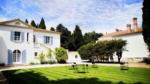 A courtyard with a white building, a lawn, and outdoor furniture. - Charming Mas for rent by the week  (Arles)