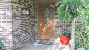 A brick house with a wooden door, a welcome sign, a potted plant, and a security sign. - Beaufort Family Home (Beaufort)